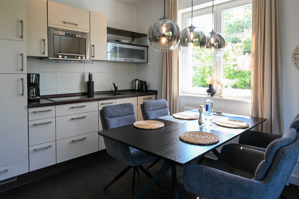 Modern kitchen and dining area in the Seeadler vacation apartment with a view of the greenery in the Hotel Künstlerquartier Seezeichen.