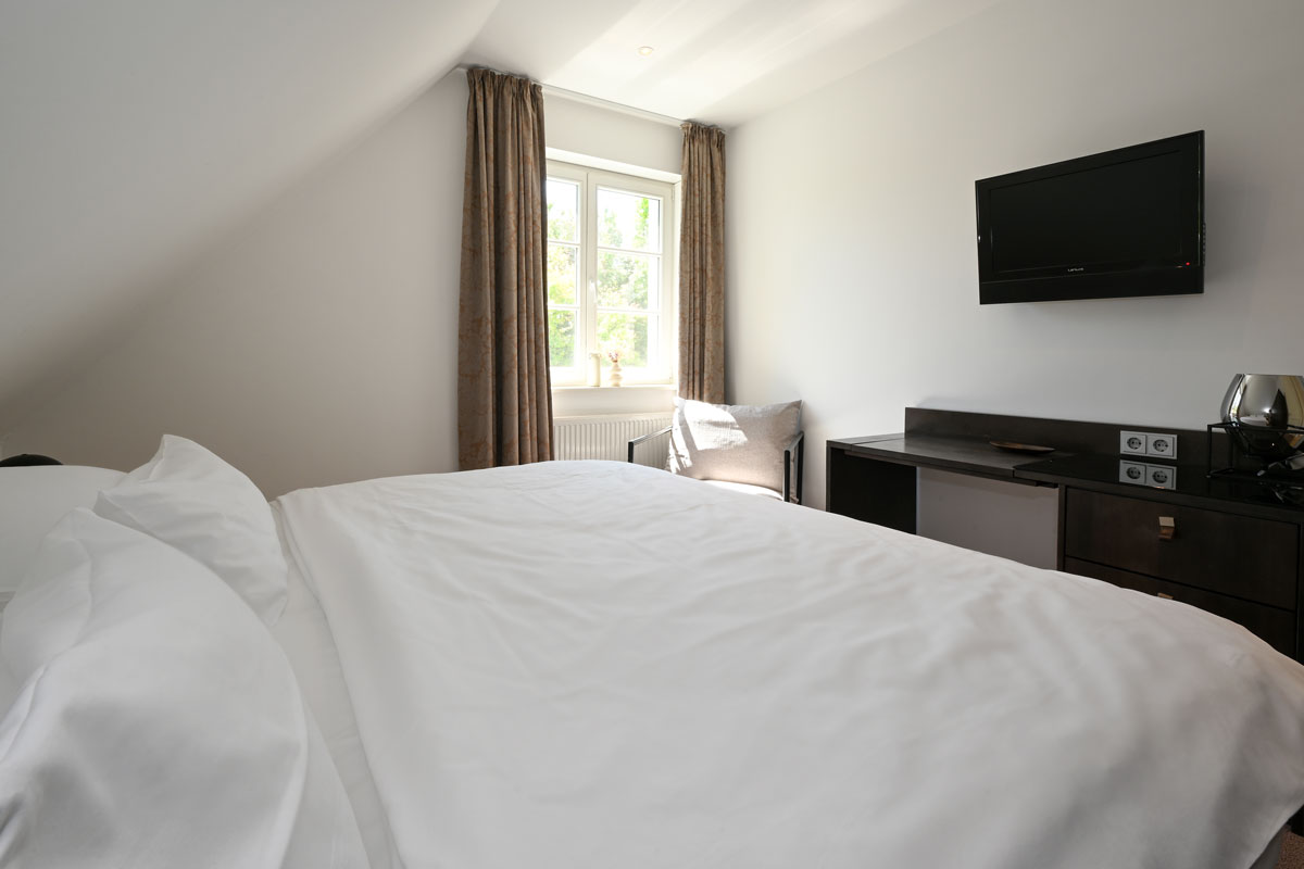 Cozy bedroom with double bed and bright window in the Seeadler vacation apartment in the Hotel Künstlerquartier Seezeichen.
