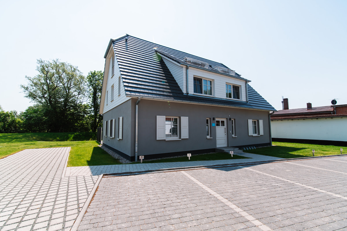 Aussenansicht der Strandvilla des Hotel Künstlerquartier Seezeichen mit der Ferienwohnung Strandjuwel und zahlreichen Parkplätzen.