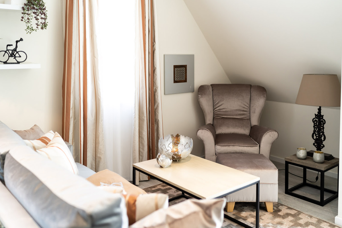 Cozy living area with bright upholstered furniture in the Strandjuwel vacation apartment in the Hotel Künstlerquartier Seezeichen.