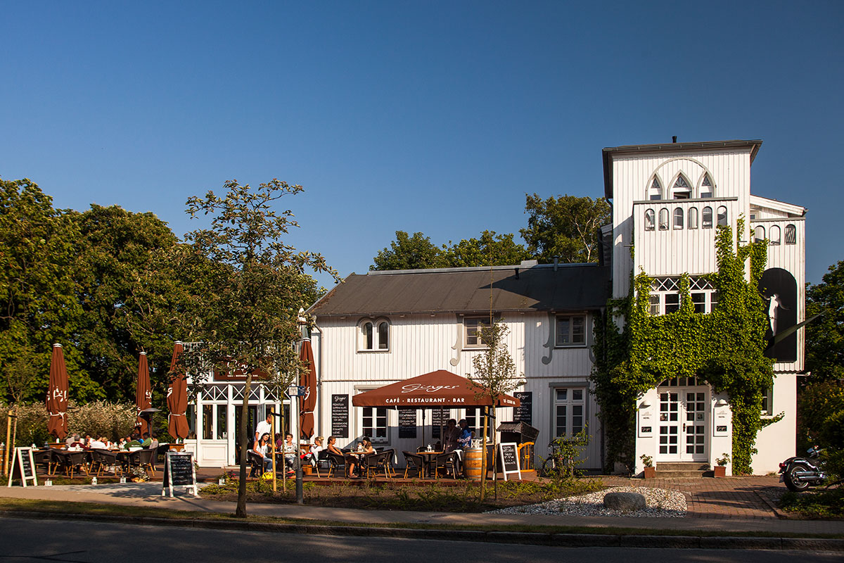 Außenansicht des Hotel Künstlerquartier Seezeichen in Ahrenshoop mit Fachwerkarchitektur und einladender Terrasse.