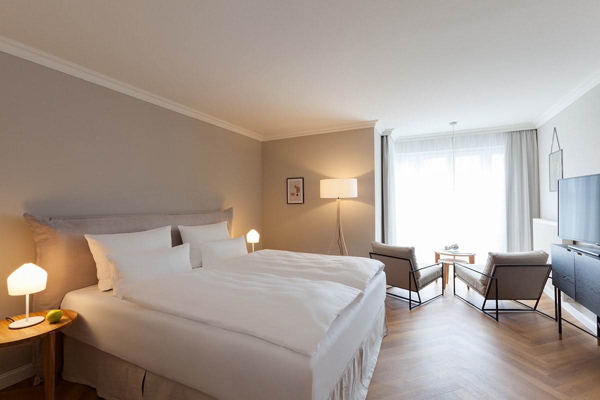 Gemütliches Doppelbett mit hochwertiger Bettwäsche und Ostseeblick im Doppelzimmer des Vju Hotels auf Rügen.