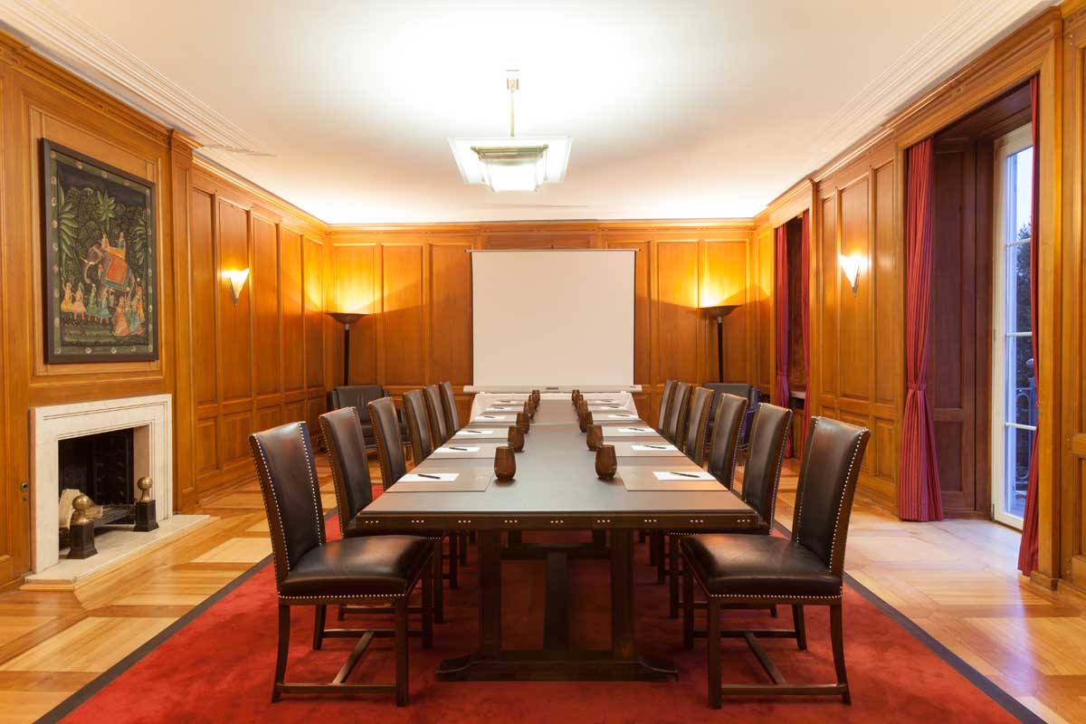 Tagungsraum im Hotel Elephant Weimar mit einem großen Konferenztisch, Lederstühlen und Holzvertäfelung bereit für Konferenzen.