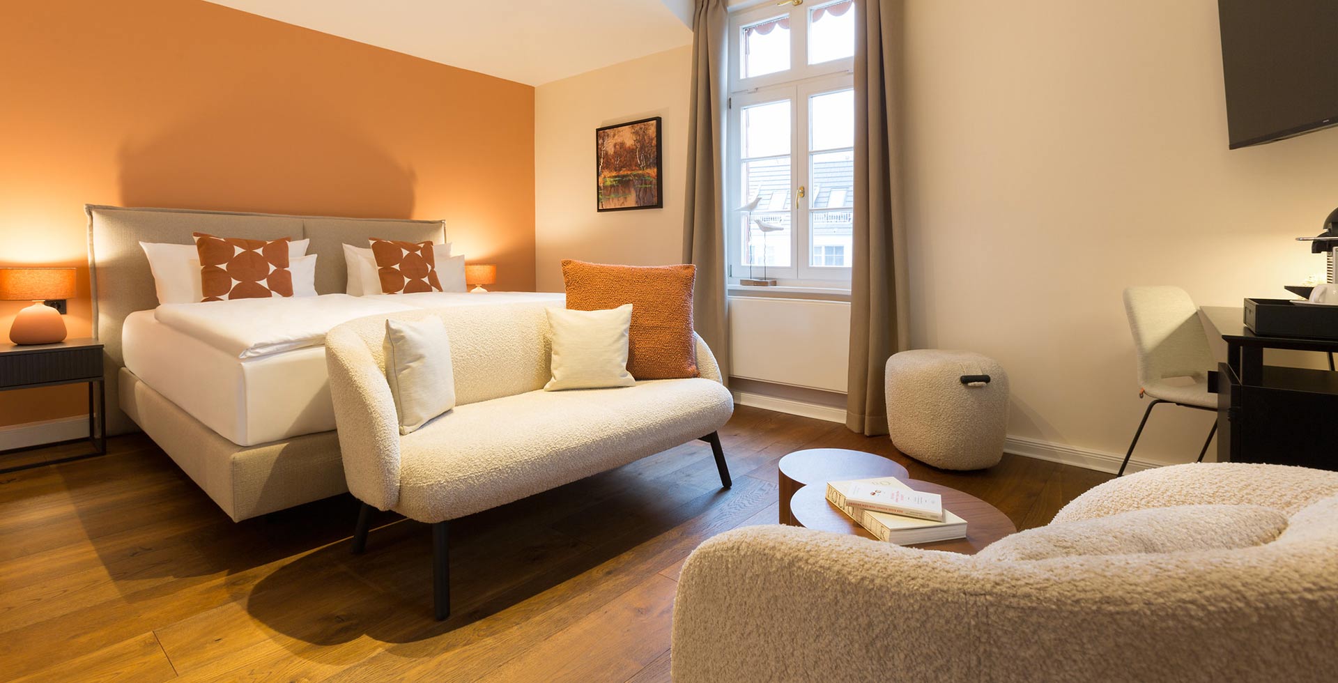 Ein stilvoll möbliertes Doppelzimmer, das warme Farben und Cremetöne mit Holz und weichen Polsterelementen vereint.